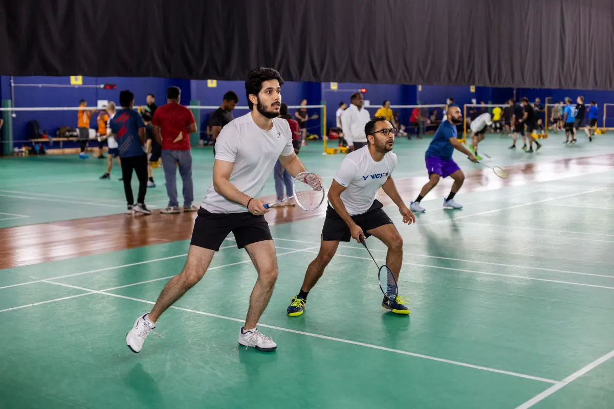 Two badminton players holding their rackets ready for the next shot on an indoor court