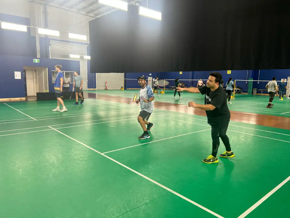 Players sharing an indoor doubles court during a WBi social badminton session