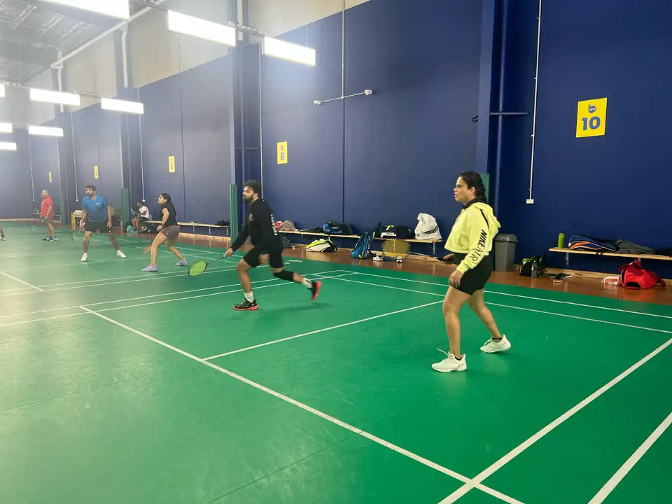 Players sharing indoor badminton courts during a WBi social session.