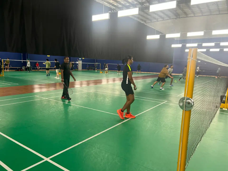 Players with rackets ready on an indoor court during a WBi social badminton session