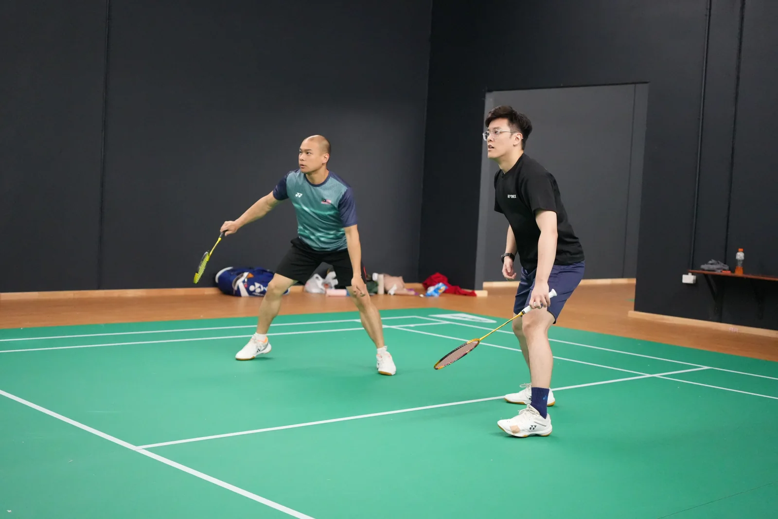 Two teammates in green and black shirts holding their rackets ready at the WBi 2026 tournament