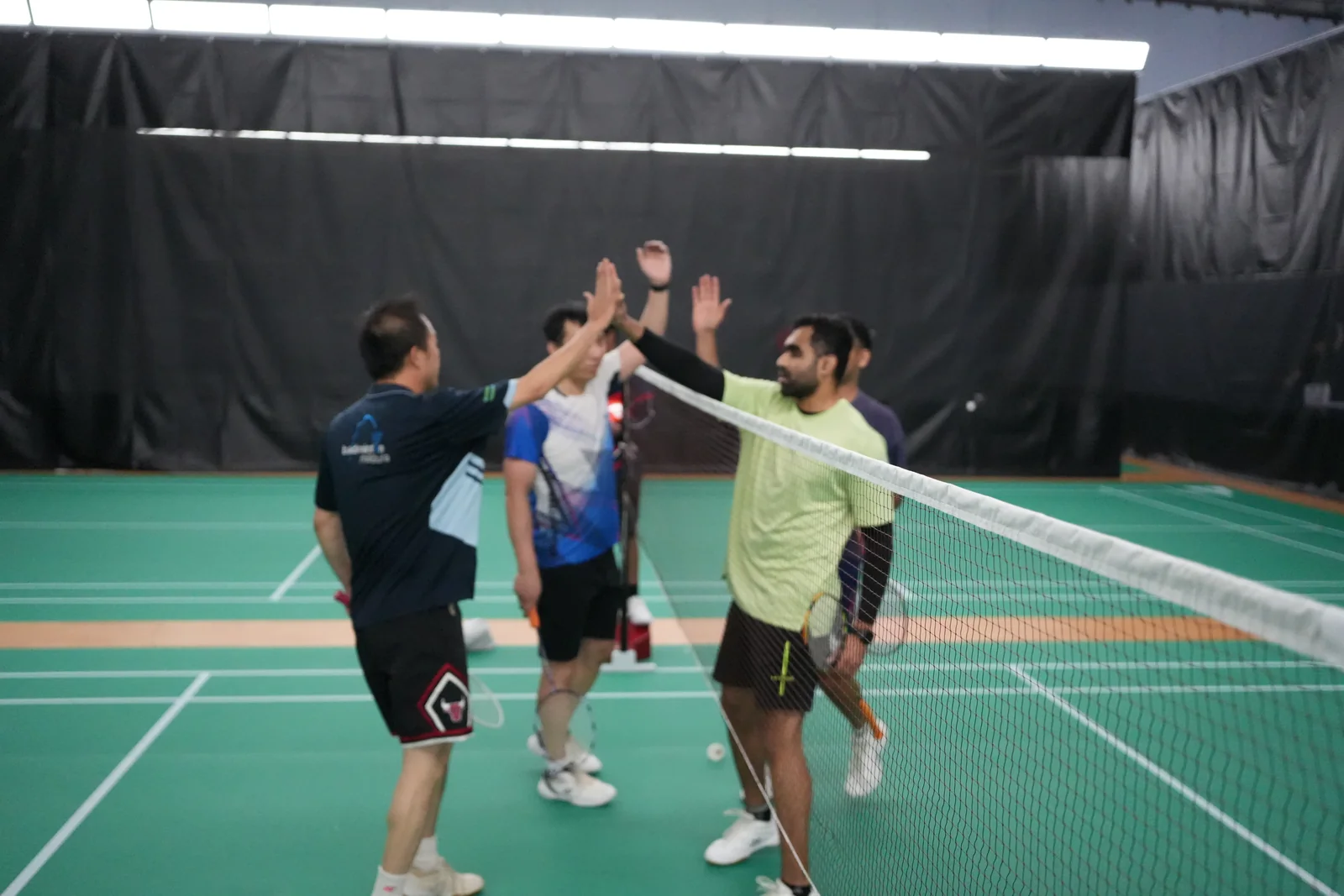Players exchanging high-fives across the badminton net